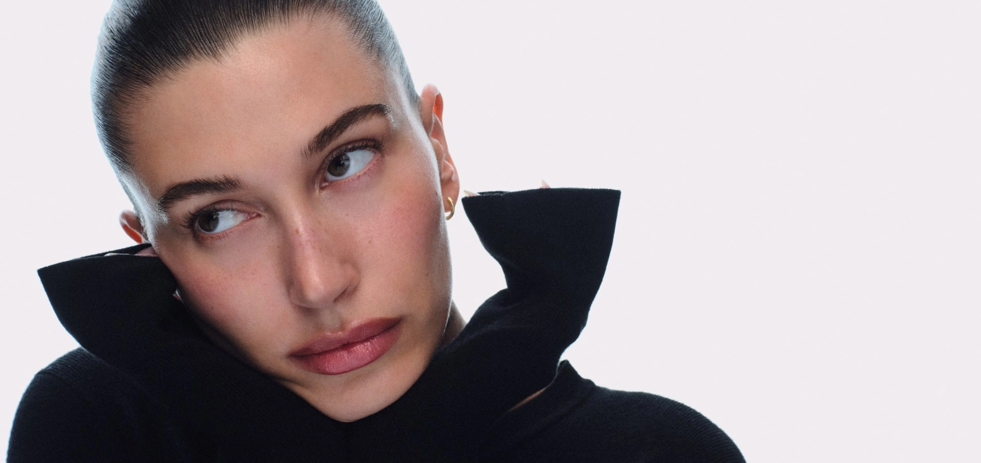 hailey in a black high-neck top against a pale lilac backdrop